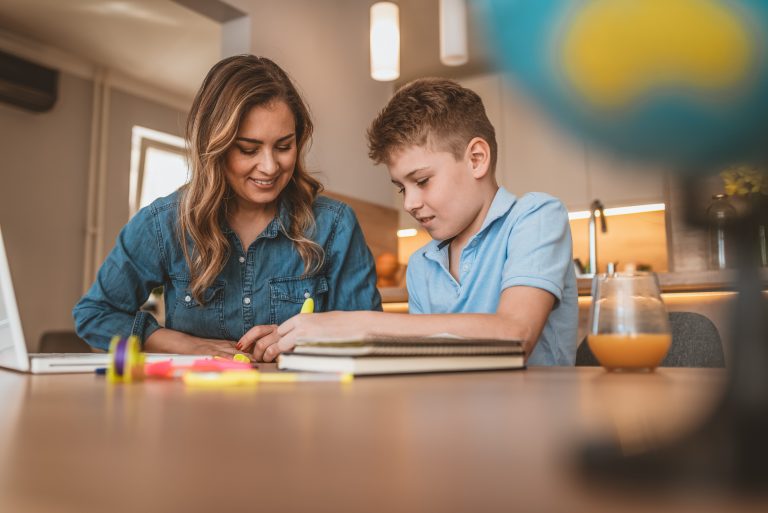 Mother helping her son with homework in the kitchen.
